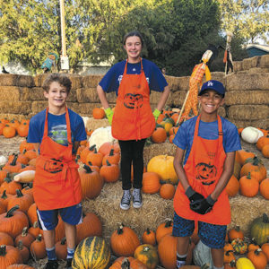 St. Brendan School eighth graders Oliver Tostado (left), Kaya Gips and Theo Collins are volunteers at Wilshire Rotary’s pumpkin patch on Larchmont Boulevard. (photo courtesy of Wendy Clifford/Wilshire Rotary)